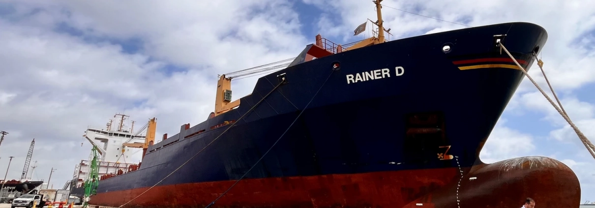 Handover of the cargo vessel “Rainer D” in the port of Miami (USA) to new owners – vessel alongside the quay with port cranes.